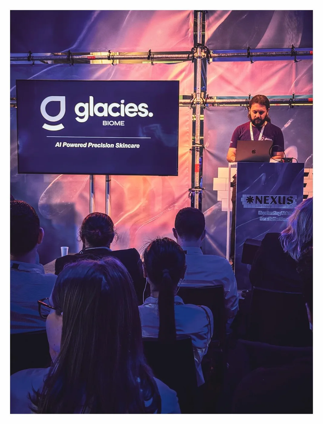 Speaker at the NEXUS lectern beside a Glacies Biome presentation screen